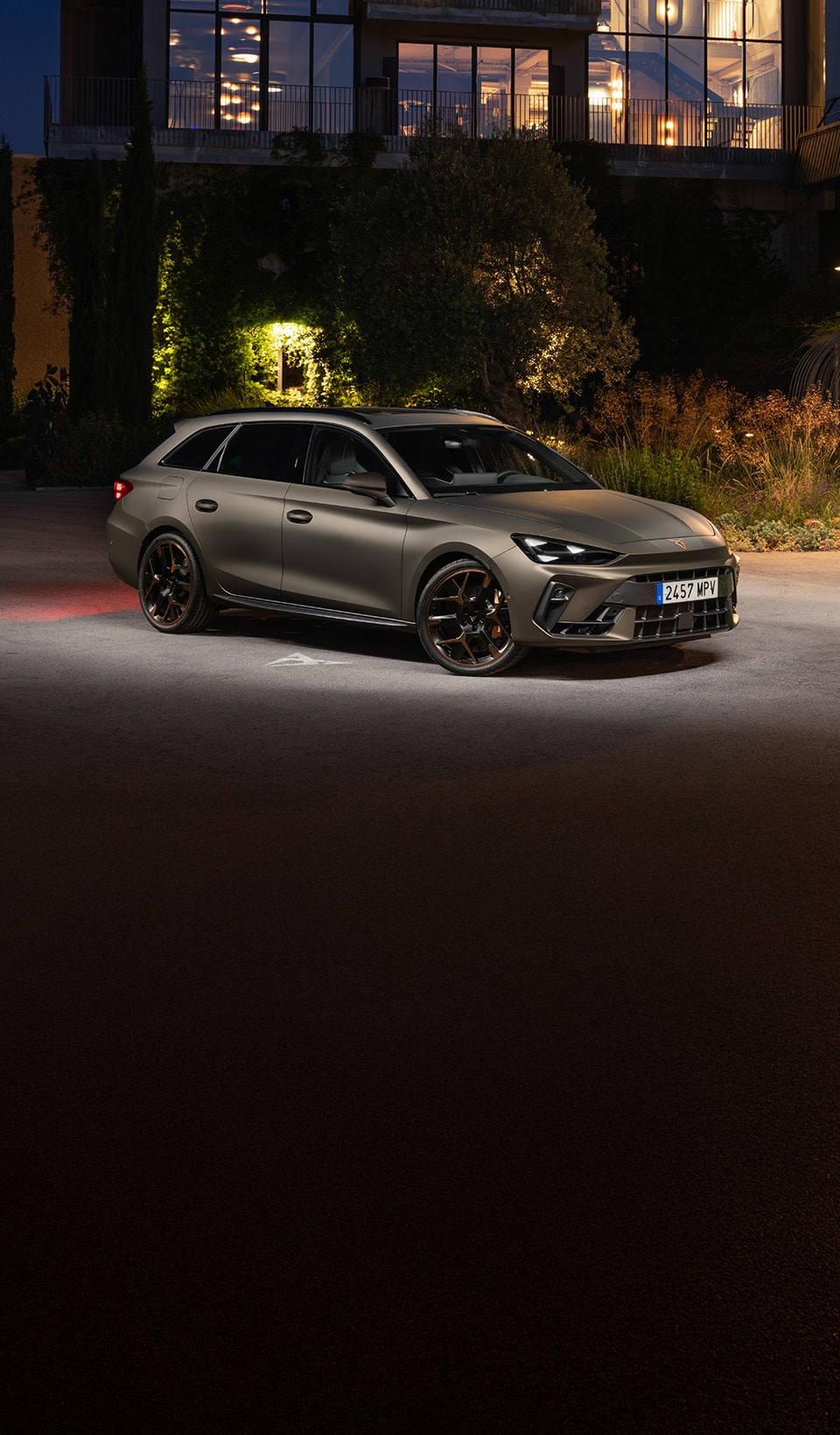 A blue CUPRA car in a surreal scene, superimposed in front of a group of people all facing away except for one man looking back at the viewer.  A blue CUPRA car in a surreal scene, superimposed in front of a group of people all facing away except for one man looking back at the viewer.