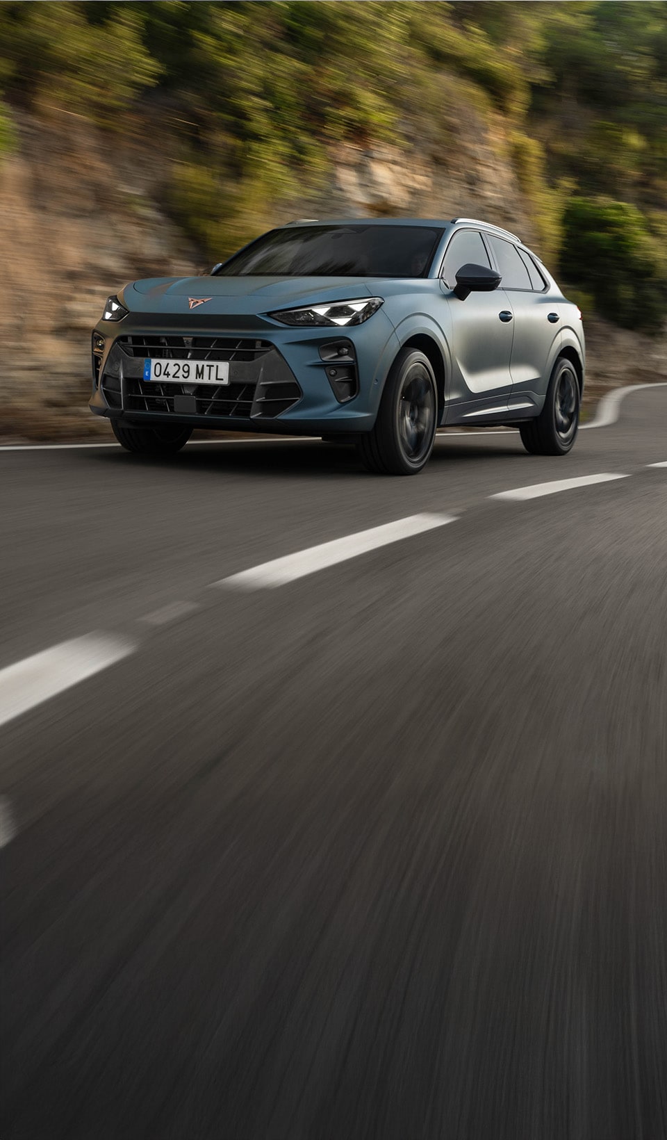 A CUPRA Leon Sportstourer shown from an elevated angle, with a person draped in dark, flowing fabric that creates a dynamic, red-lit trail beside the car. A CUPRA Leon Sportstourer shown from an elevated angle, with a person draped in dark, flowing fabric that creates a dynamic, red-lit trail beside the car.