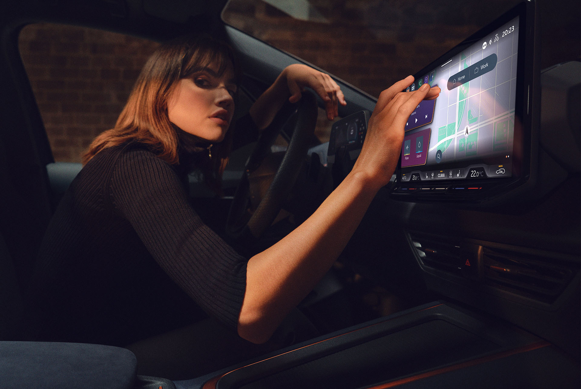 Una donna all'interno di una CUPRA Born che utilizza la plancia e lo schermo dell'infotainment