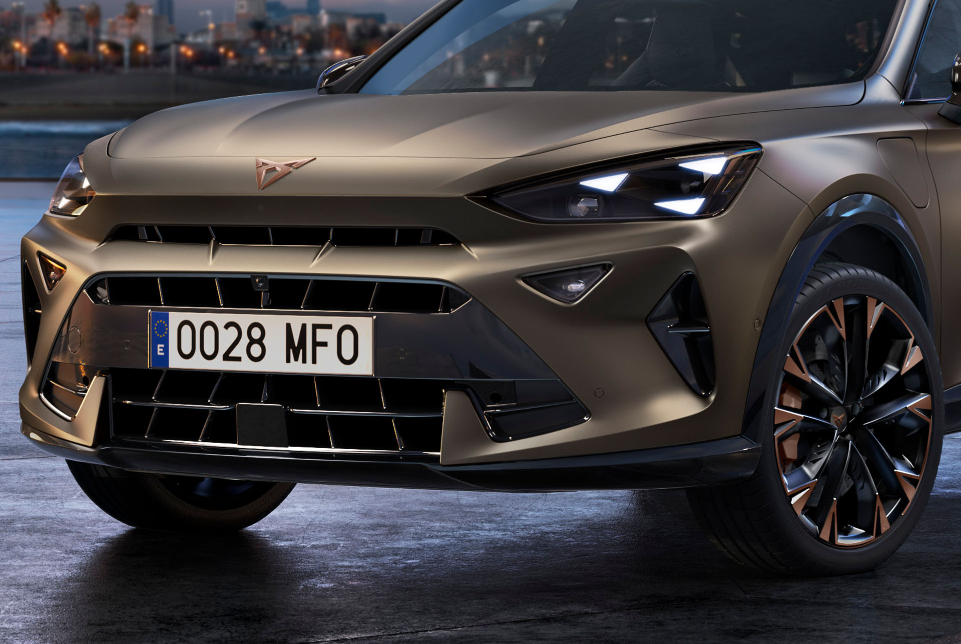 Primo piano del frontale di una nuova CUPRA Formentor 2024 stile CUV color Bronzo Century opaco con cerchi impreziositi da dettagli in rame, fari anteriori con firma luminosa a forma triangolare e distintivo logo CUPRA.