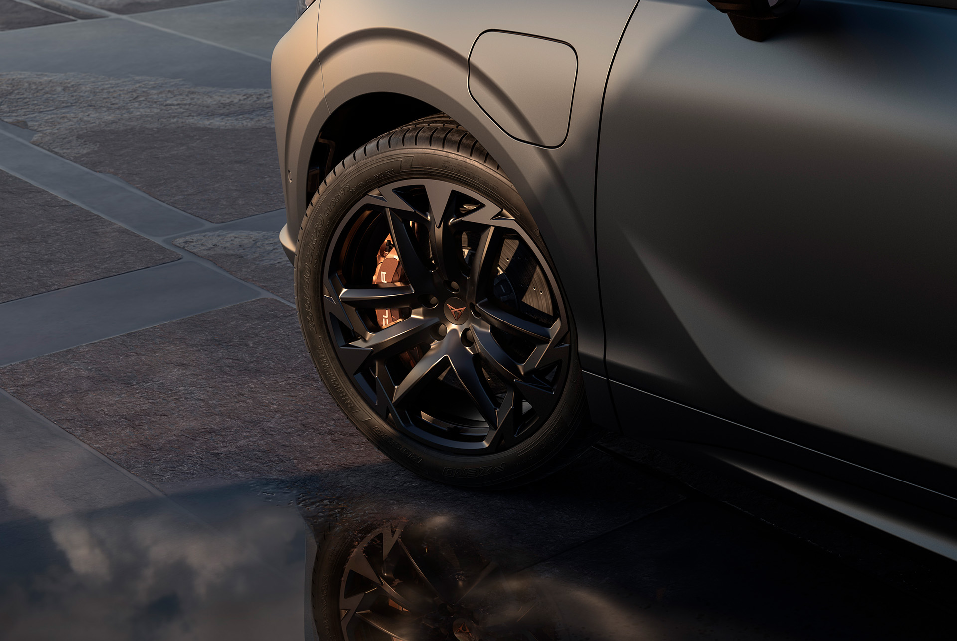 20 inch america's cup wheel on the new cupra terramar, in black with copper accents. Background includes a tiled pavement and part of the car's glossy, dark body.